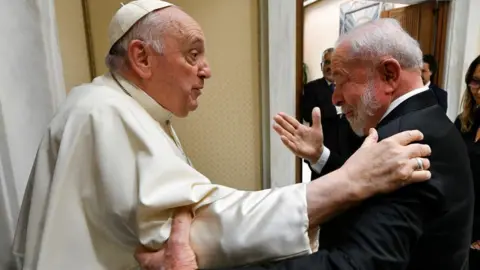Vatican Media/­Handout via Reuters Pope Francis and Brazil's President Luiz Inácio Lula da Silva greet each other, holding one another's elbow and shoulder, while talking, at the Vatican